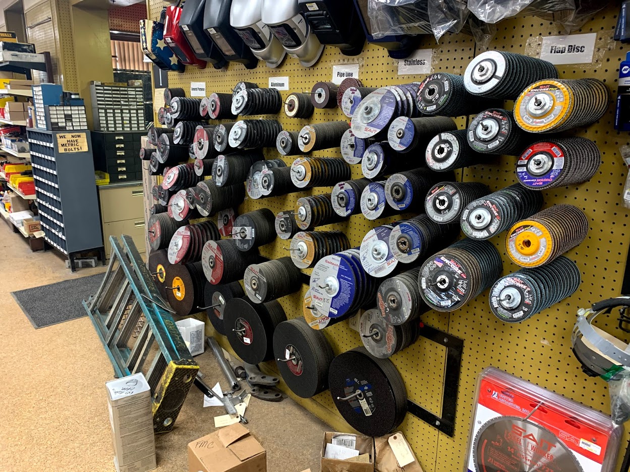 Full pegboard wall of SAIT cutting and grinding discs at Riggs Machine & Welding in Stephenville, TX — sorted by general purpose, aluminum, pipeline, stainless, and flap disc