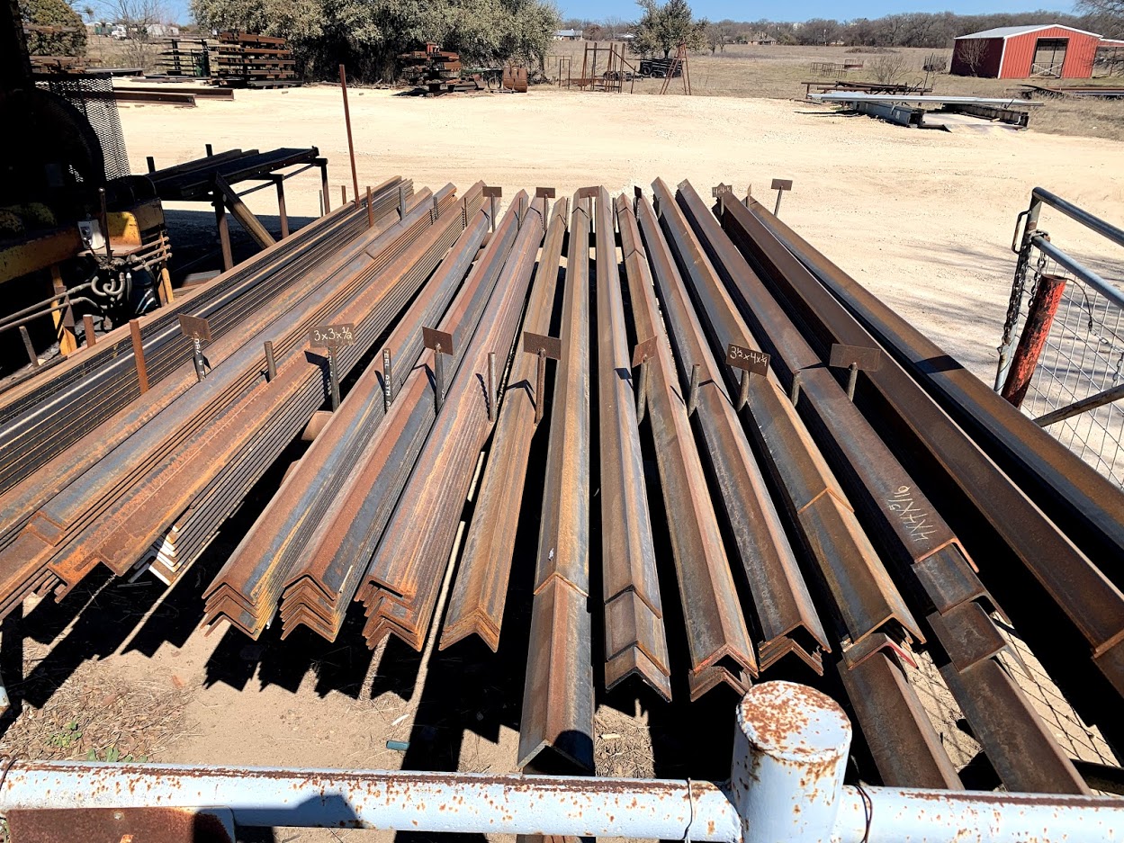Steel angle iron sorted by size with labeled tags at Riggs Machine & Welding yard in Stephenville, TX