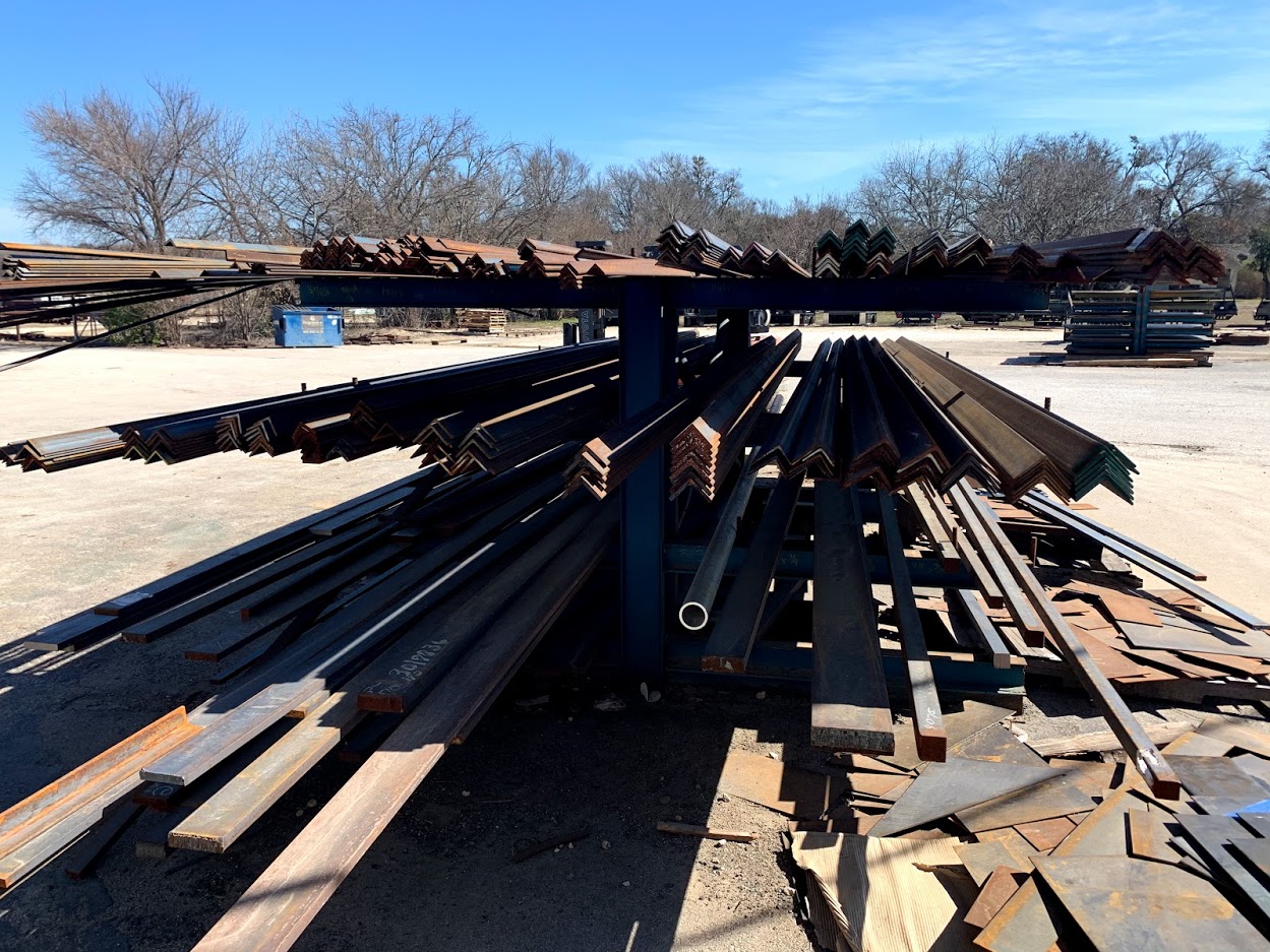 Steel angle iron, flat bar, and pipe on a cantilever rack at Riggs Machine & Welding in Stephenville, TX