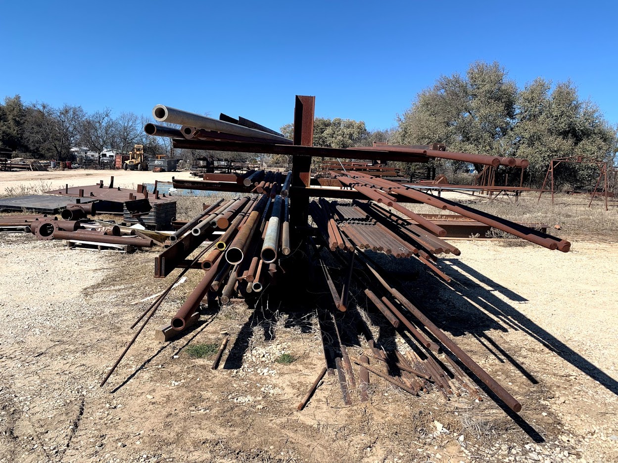 Pipe, round bar, rod, and specialty steel stock on wall-mounted indoor racks at Riggs Machine & Welding supply, Stephenville, TX
