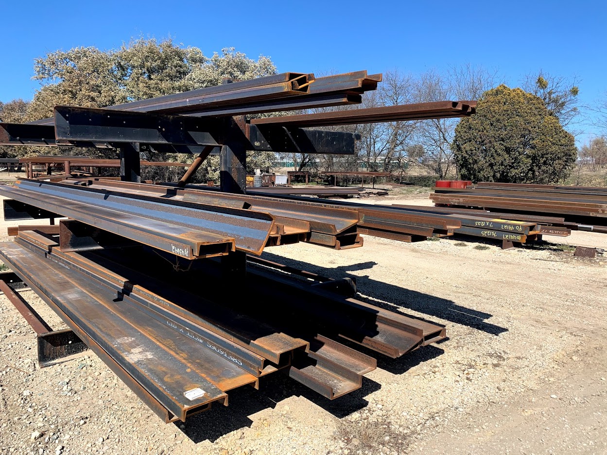 Flat-stacked steel channel iron in long lengths at Riggs Machine & Welding outdoor yard, Stephenville, TX