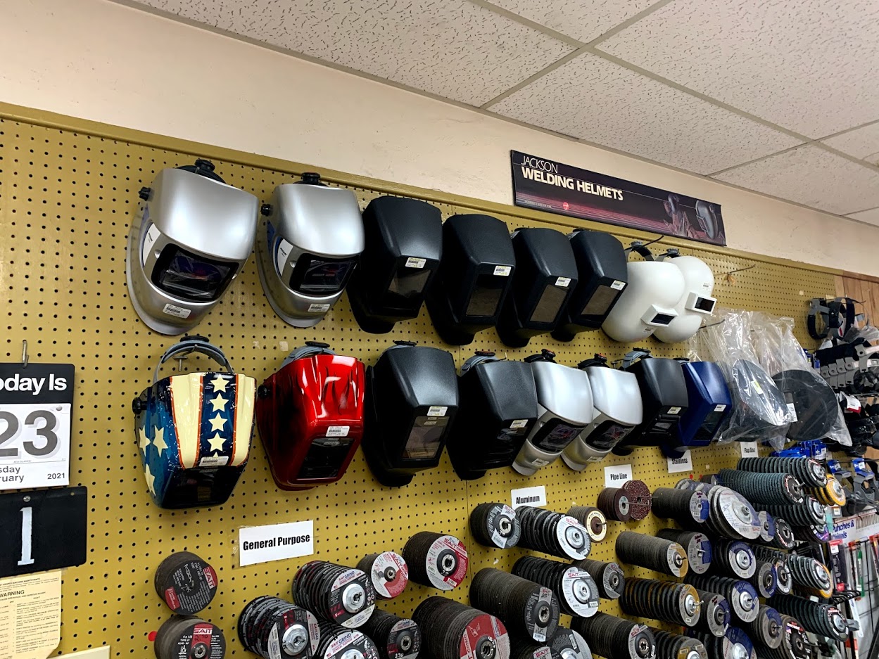 Jackson welding helmets including auto-darkening and standard models on pegboard at Riggs Machine & Welding supply store in Stephenville, TX