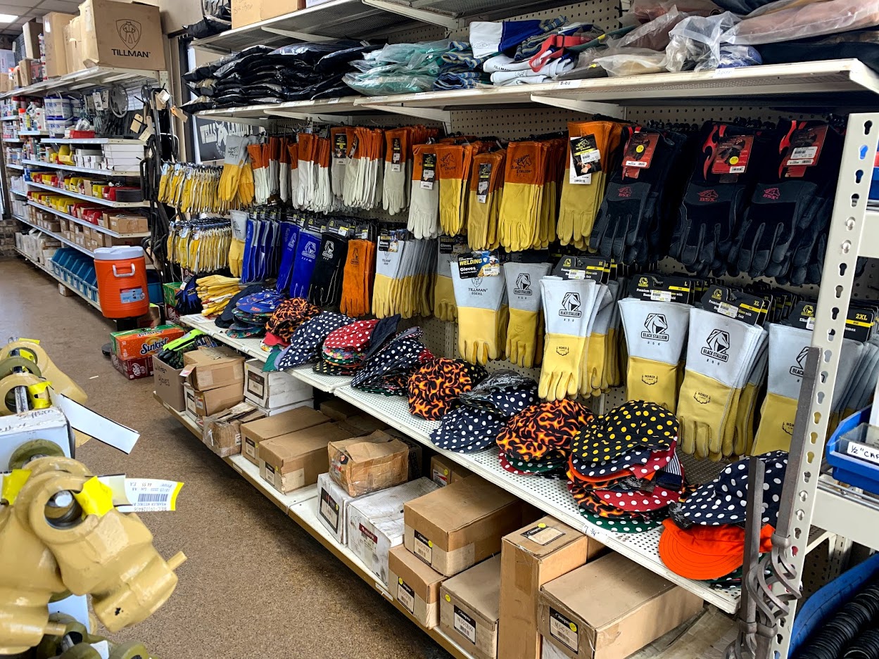 Tillman and Black Stallion welding gloves, welding caps, and PPE on supply shelves at Riggs Machine & Welding in Stephenville, TX