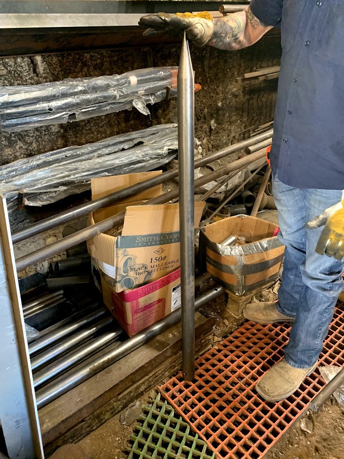 Riggs Machine & Welding employee holding a freshly fabricated steel hay spear point in the shop in Stephenville, TX