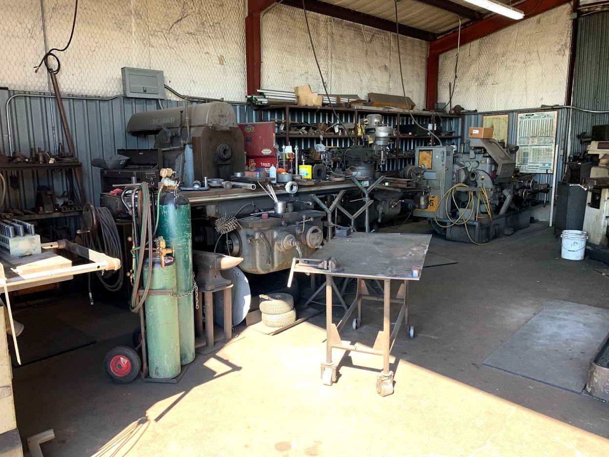 Lathes, milling machines, and gas cylinders inside the Riggs Machine & Welding shop in Stephenville, TX