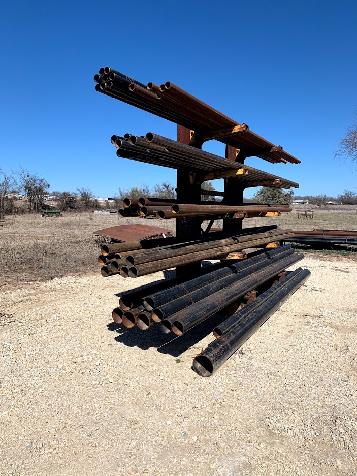 Multi-tier pipe rack stocked with black steel pipe in several diameters at Riggs Machine & Welding yard, Stephenville, TX