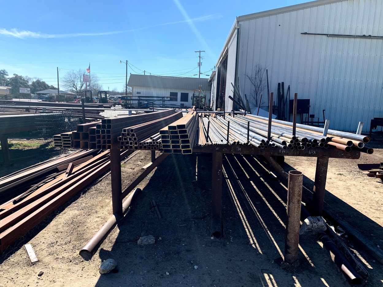 Large stock of square and rectangular steel tubing at Riggs Machine & Welding, Stephenville, TX — American flag visible in background