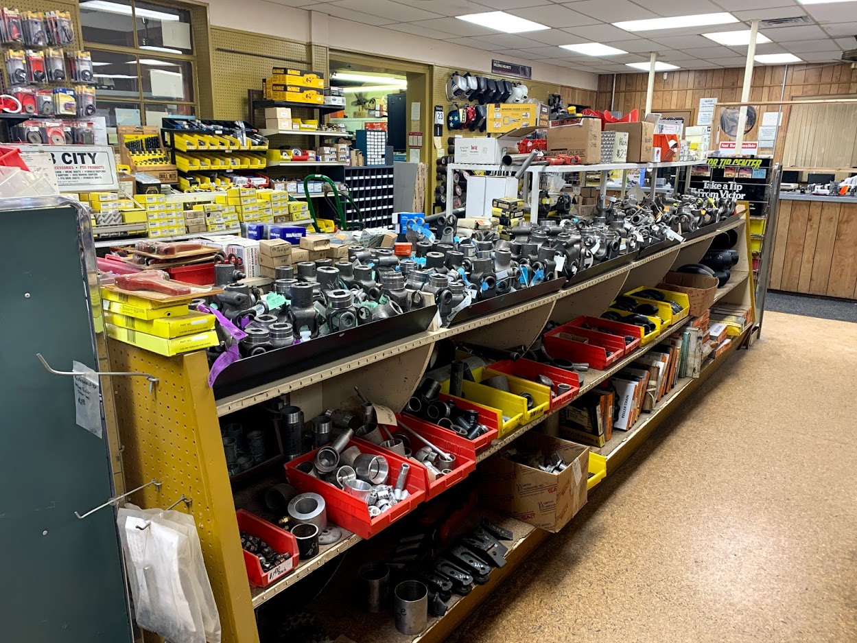Wide view of the Riggs Machine & Welding supply store in Stephenville, TX — long shelf of black iron fittings, DeWalt tools, and welding helmets
