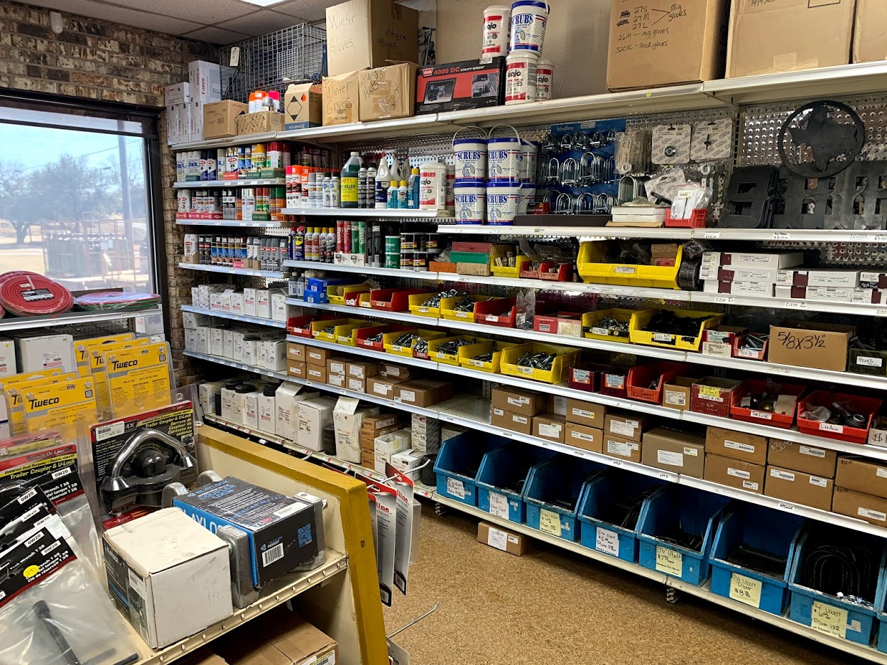 Hardware and fastener shelves at Riggs Machine & Welding in Stephenville, TX — spray paints, Scrubs hand wipes, Tweco MIG tips, and trailer couplers