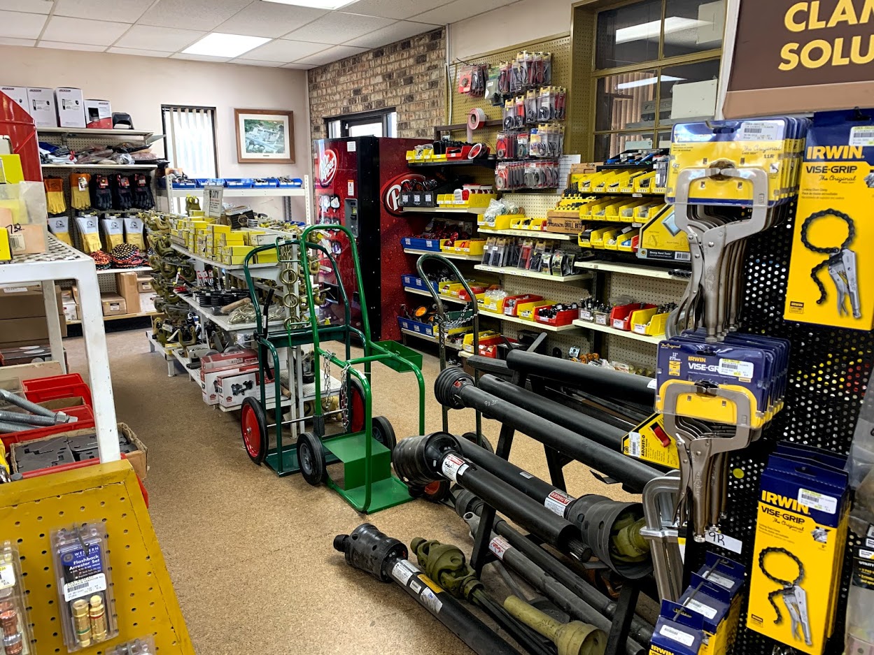 Miller Bobcat 300 welder for sale at Riggs Machine & Welding supply counter in Stephenville, TX, with hard hats and Jackson safety glasses nearby